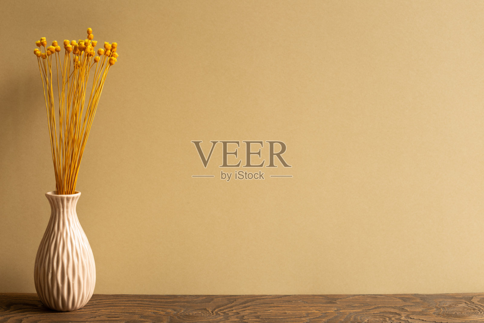 棕色背景的木桌上放着一瓶黄色干花。本空间照片摄影图片