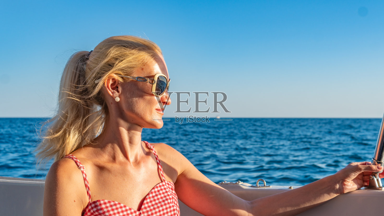 开朗的女孩在游艇上休息,用温柔的双唇环抱着大海,在太阳镜的概念里比较美丽的地平线照片摄影图片