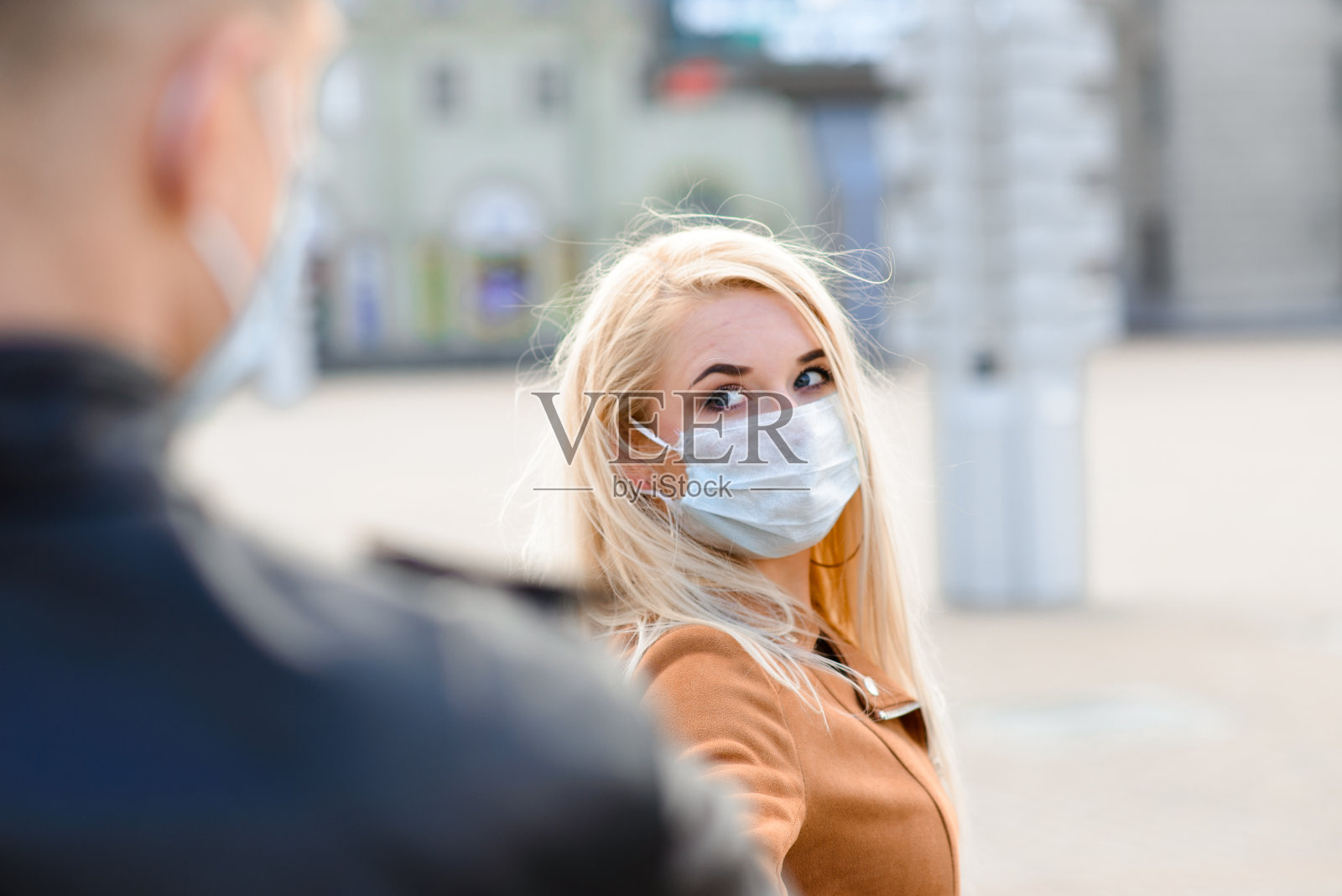 戴着面具的年轻夫妇在城市街道上。照片摄影图片