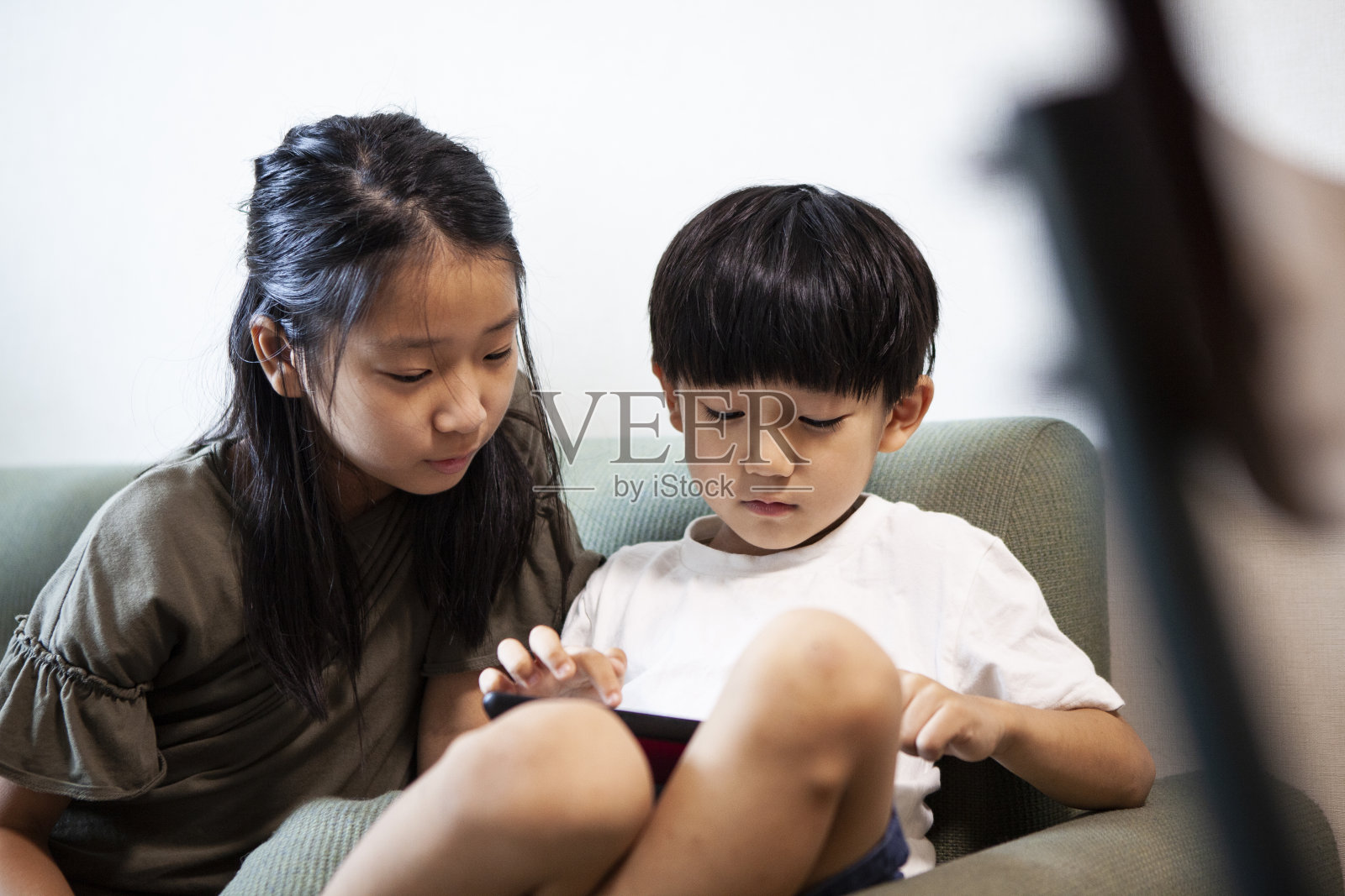 孩子们坐在沙发上玩着平板电脑照片摄影图片