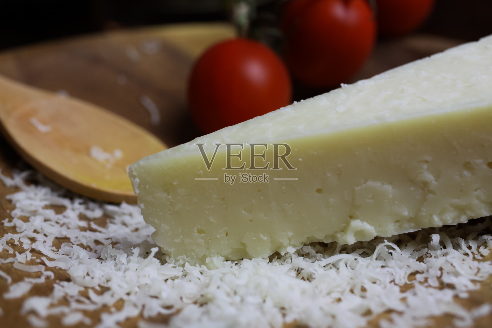 特写:整片意大利羊乳干酪放在木盘子上,配上番茄和新鲜磨碎的勺子照片摄影图片