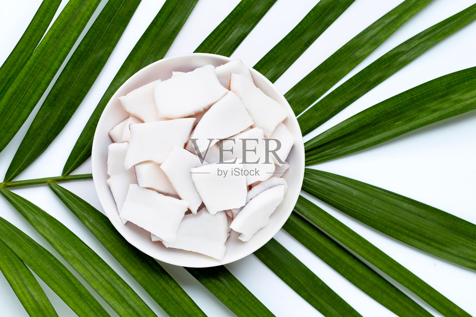 椰片装盘,放在热带棕榈叶上。照片摄影图片