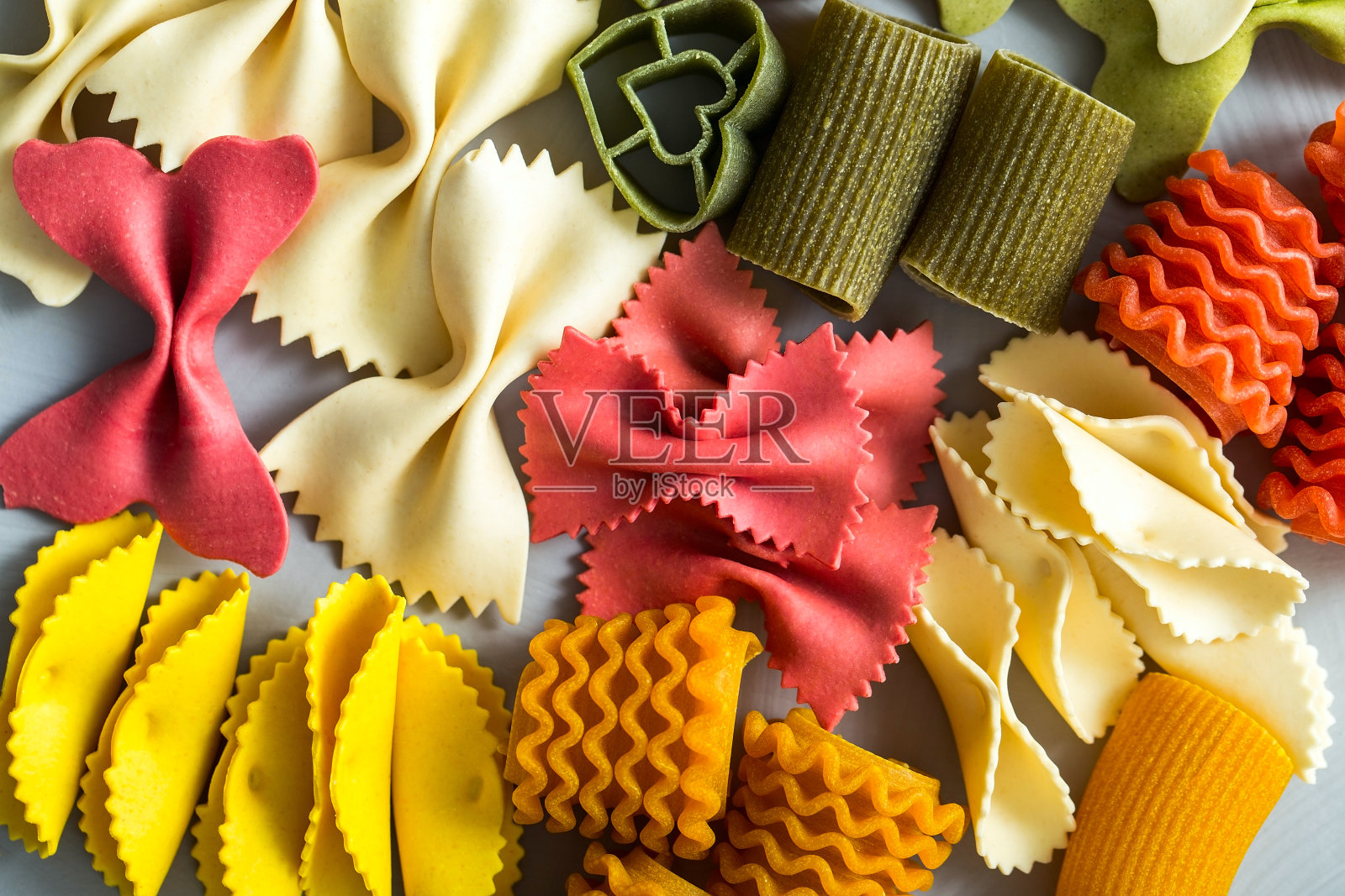 彩色意大利面特写。手工制作的意大利面有蝴蝶、蝴蝶结、管状、花瓣、心形等。照片摄影图片