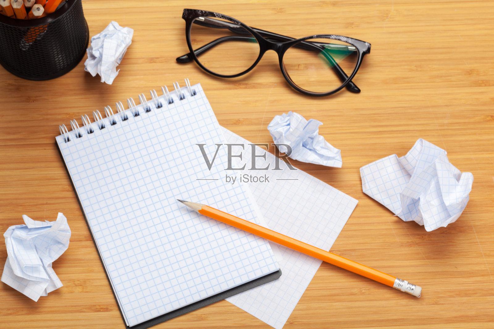 木桌上的白色记事本。在记事本周围放着许多皱巴巴的纸照片摄影图片