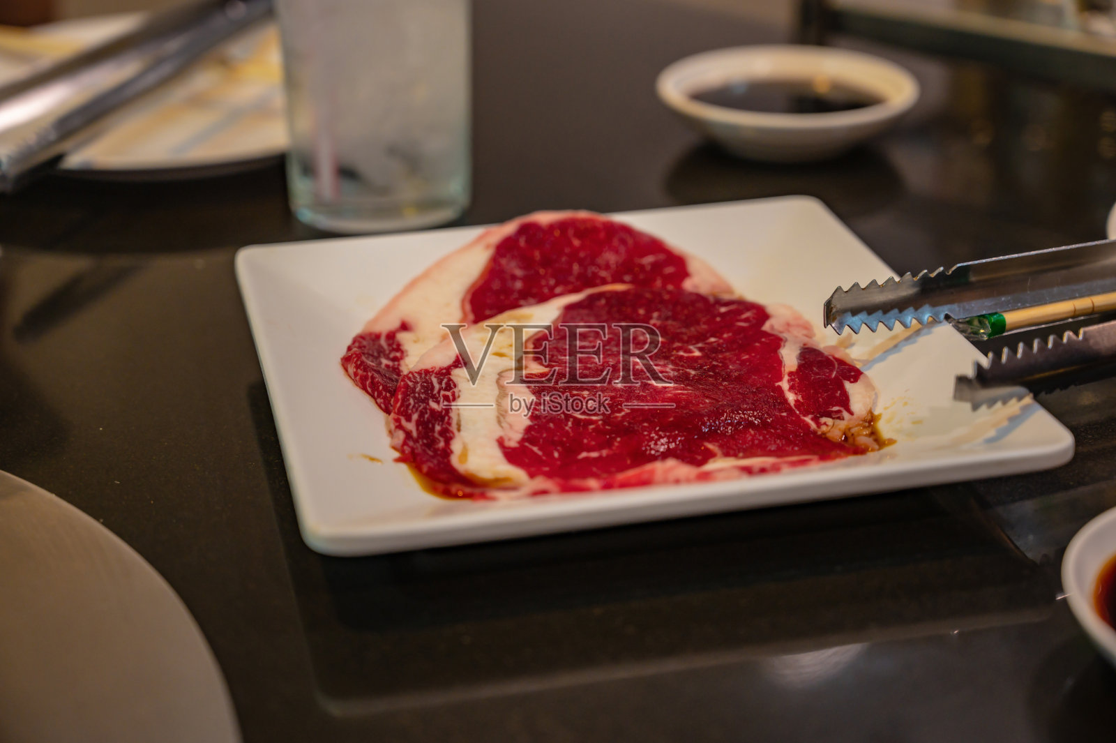 靠近生肋眼切片在烧烤自助餐餐厅的白色盘子照片摄影图片