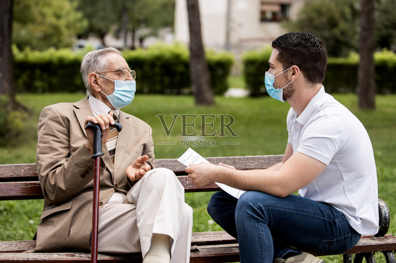 两代人,一个孙子和一个祖父,坐在长凳上讨论他们祖父的血检结果照片摄影图片