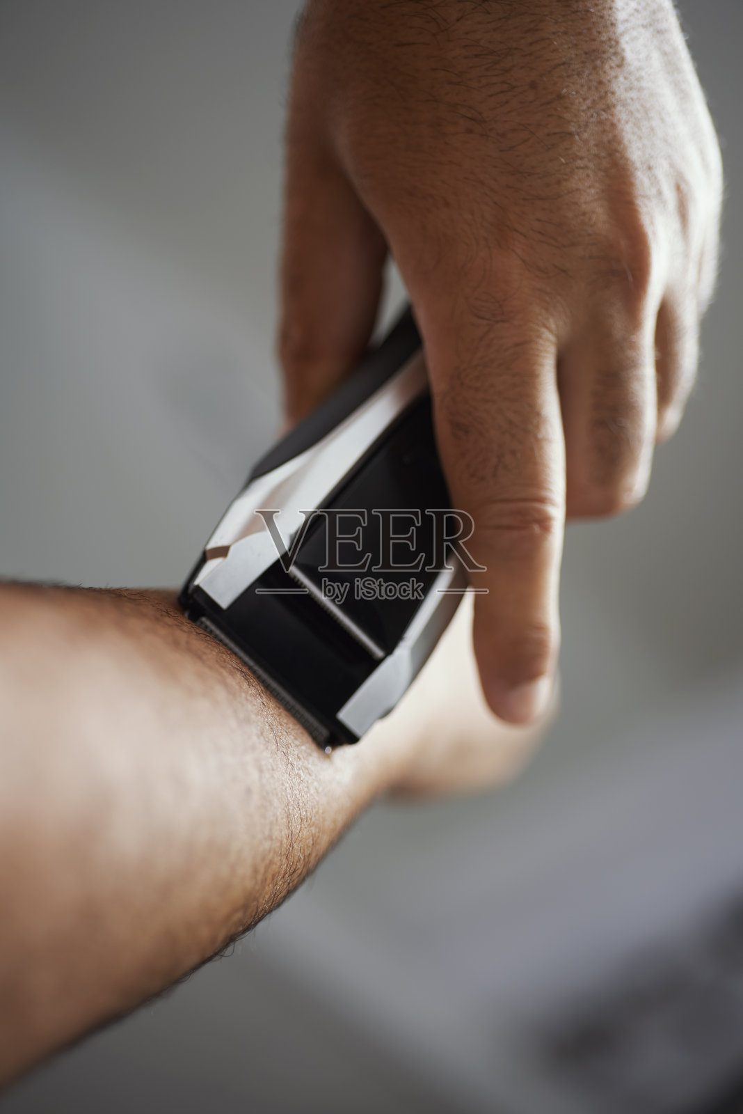 一个人正在用电动修剪器修剪他的手臂照片摄影图片