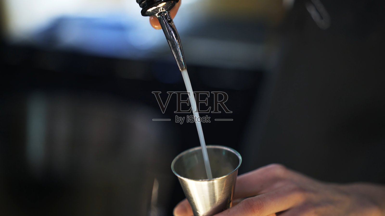 调酒师将酒精倒入金属玻璃杯,特写镜头照片摄影图片