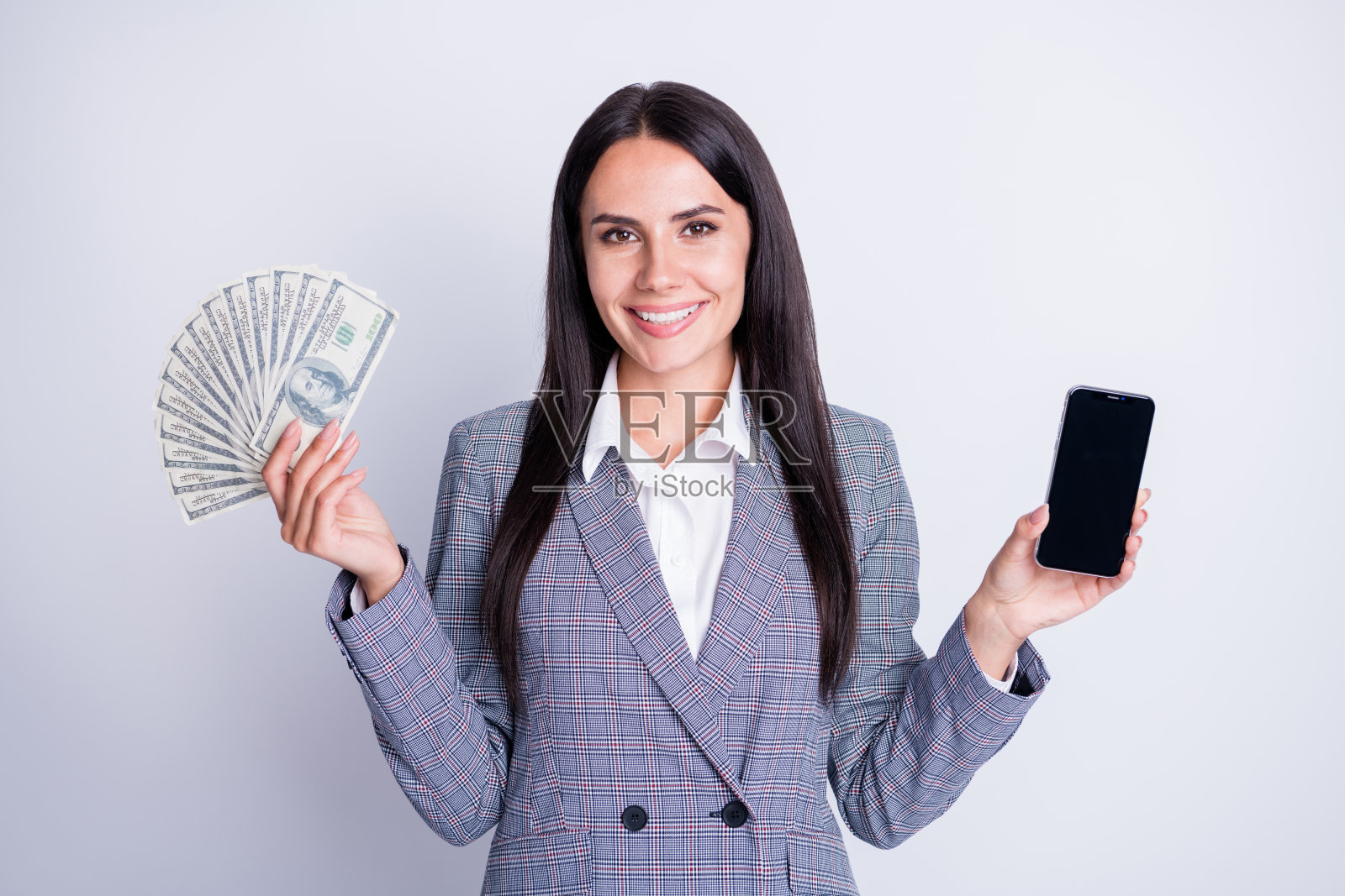 迷人的销售经理女士的照片拿着电话小装置包装美国美元买家富人想要新的电话正装格子西装孤立的灰色背景照片摄影图片