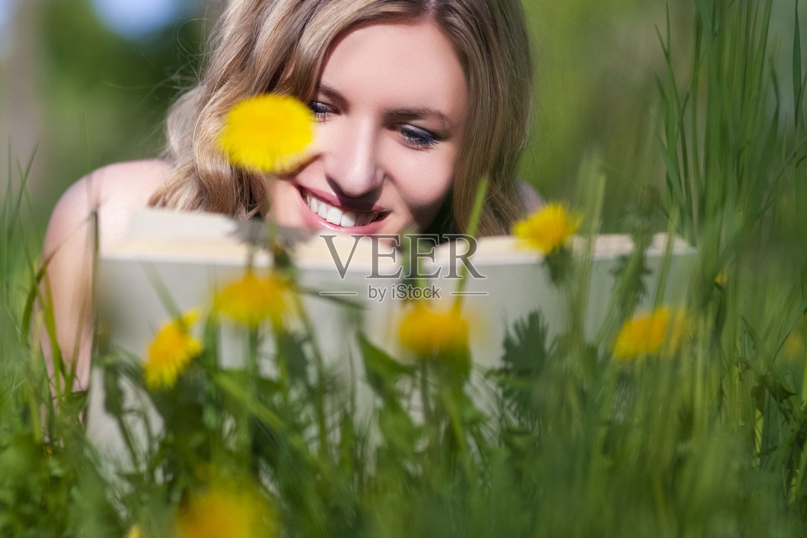 幸福的白人女性与书阅读户外草坪特写肖像。水平射照片摄影图片