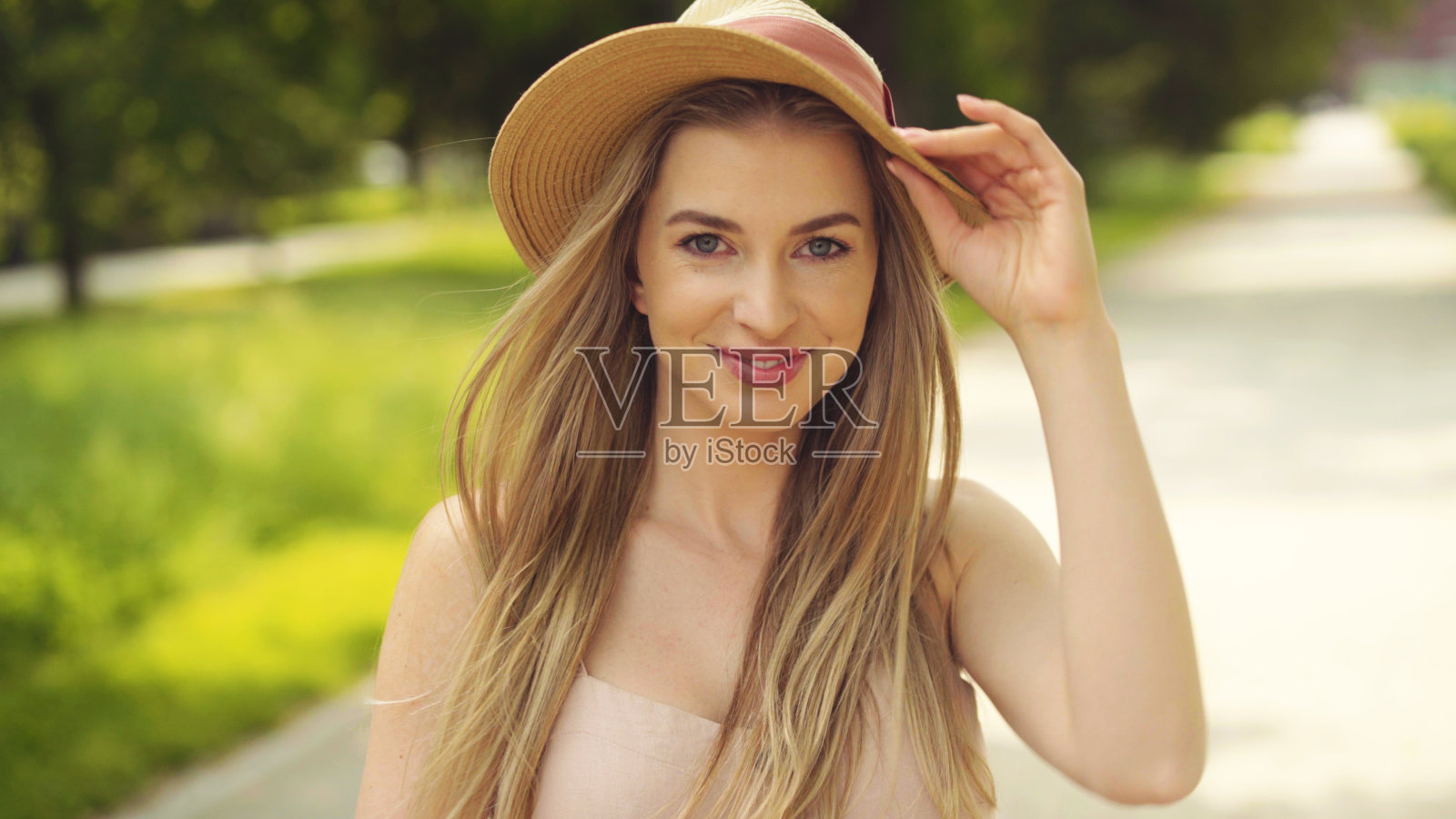 美丽的金发女人的肖像戴着帽子花时间在一个城市。照片摄影图片