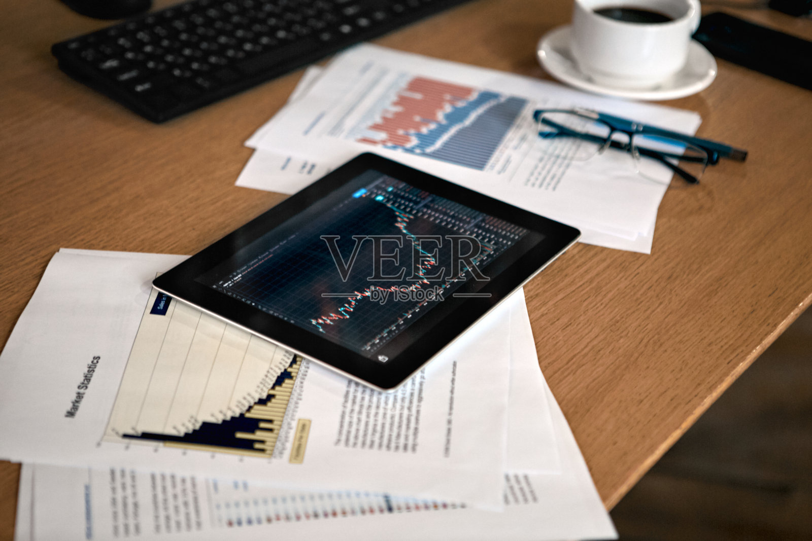 股票交易。交易员工作场所与世隔绝,没有人杯咖啡文件和数字平板电脑与价格流蜡烛酒吧在书桌上近距离照片摄影图片