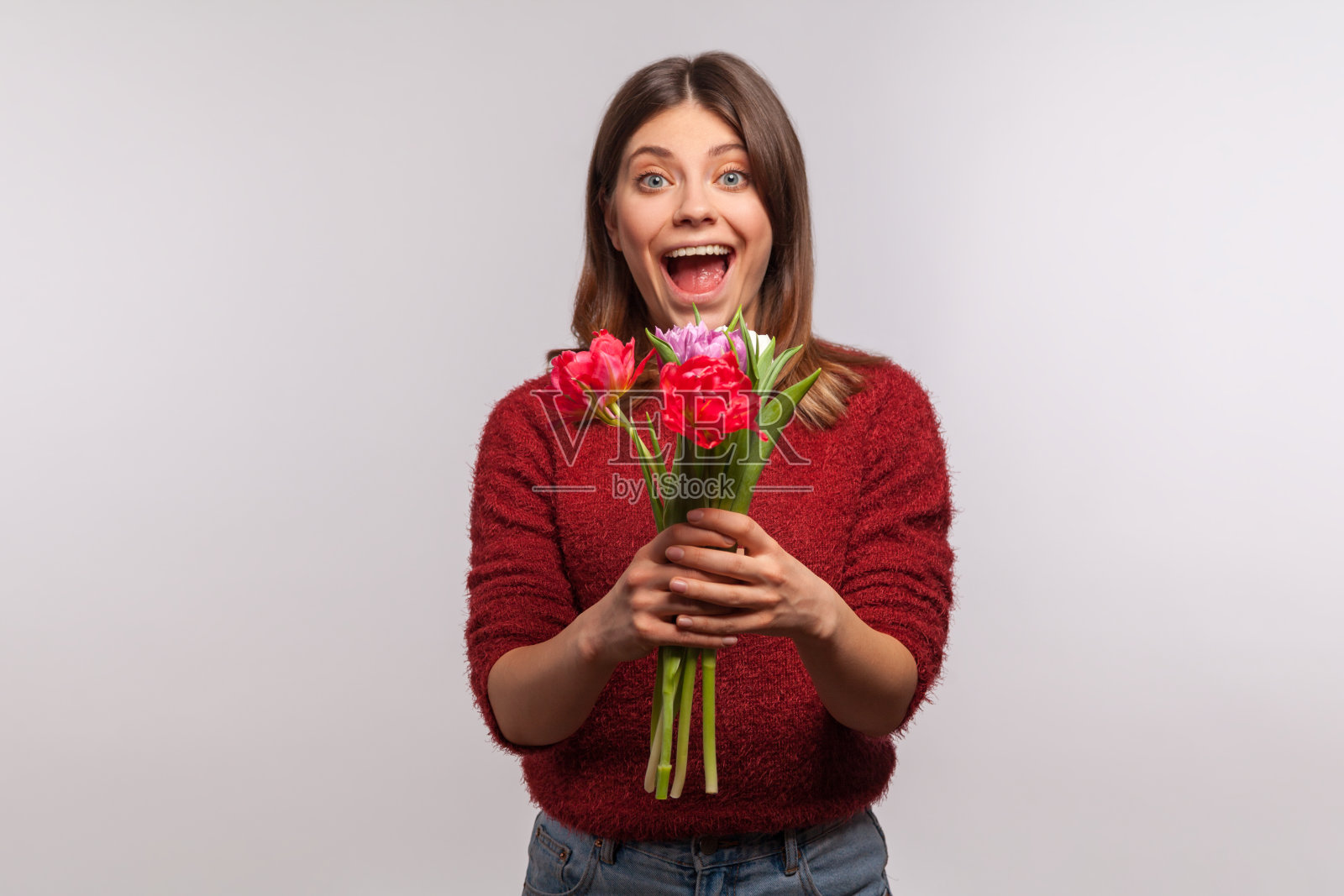 肖像惊讶的女孩站在张开的嘴,拿着一束郁金香,看着镜头惊讶高兴照片摄影图片