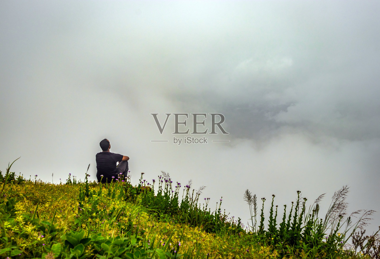 人孤立地在山顶感受宁静的自然,前景中有惊人的云层照片摄影图片