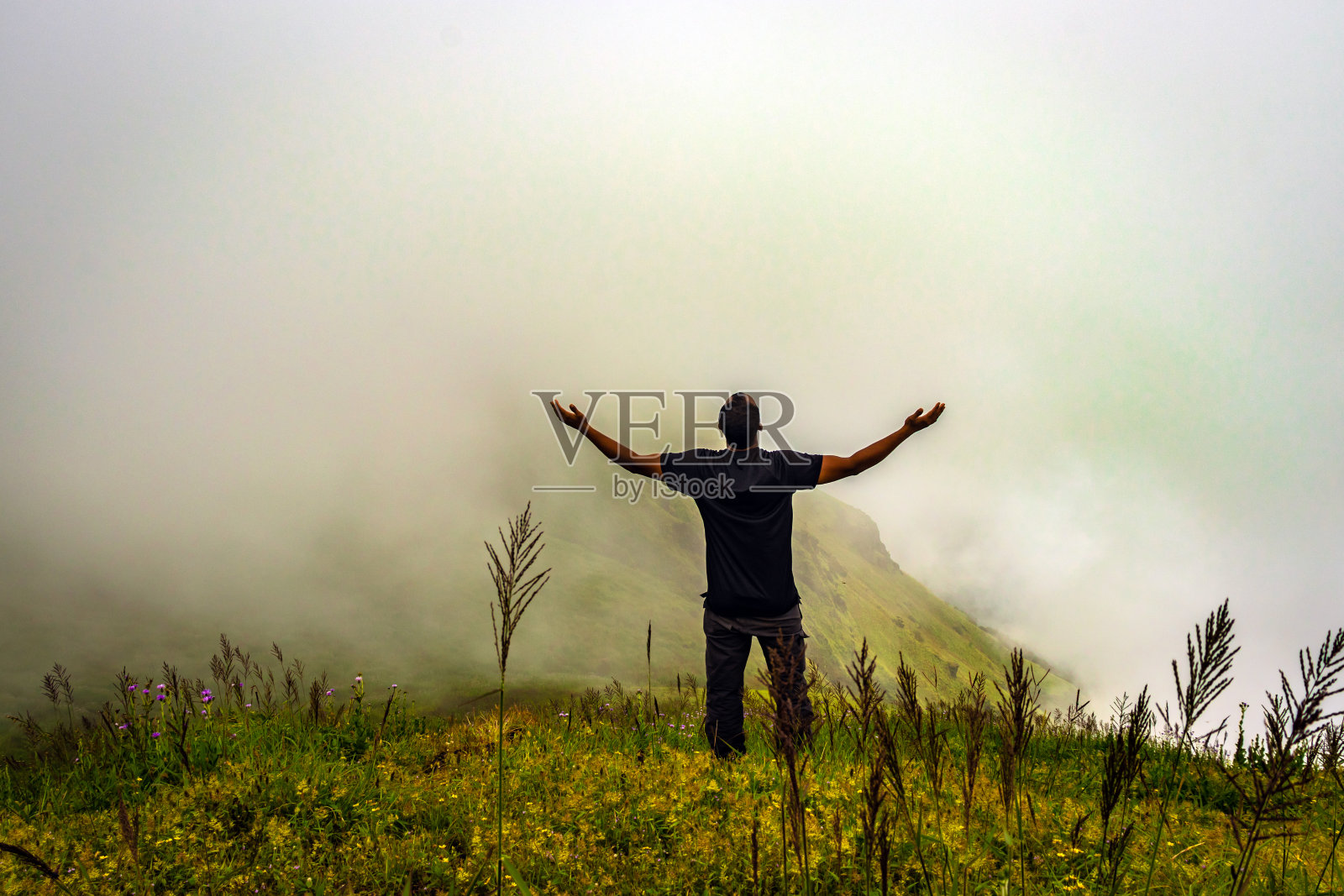 人孤立地在山顶感受宁静的自然,前景中有惊人的云层照片摄影图片