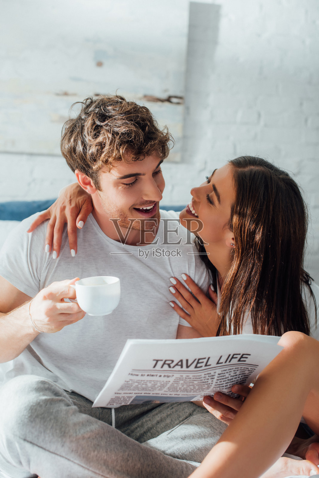 选择性的关注女人抱着咖啡杯和报纸看男朋友照片摄影图片