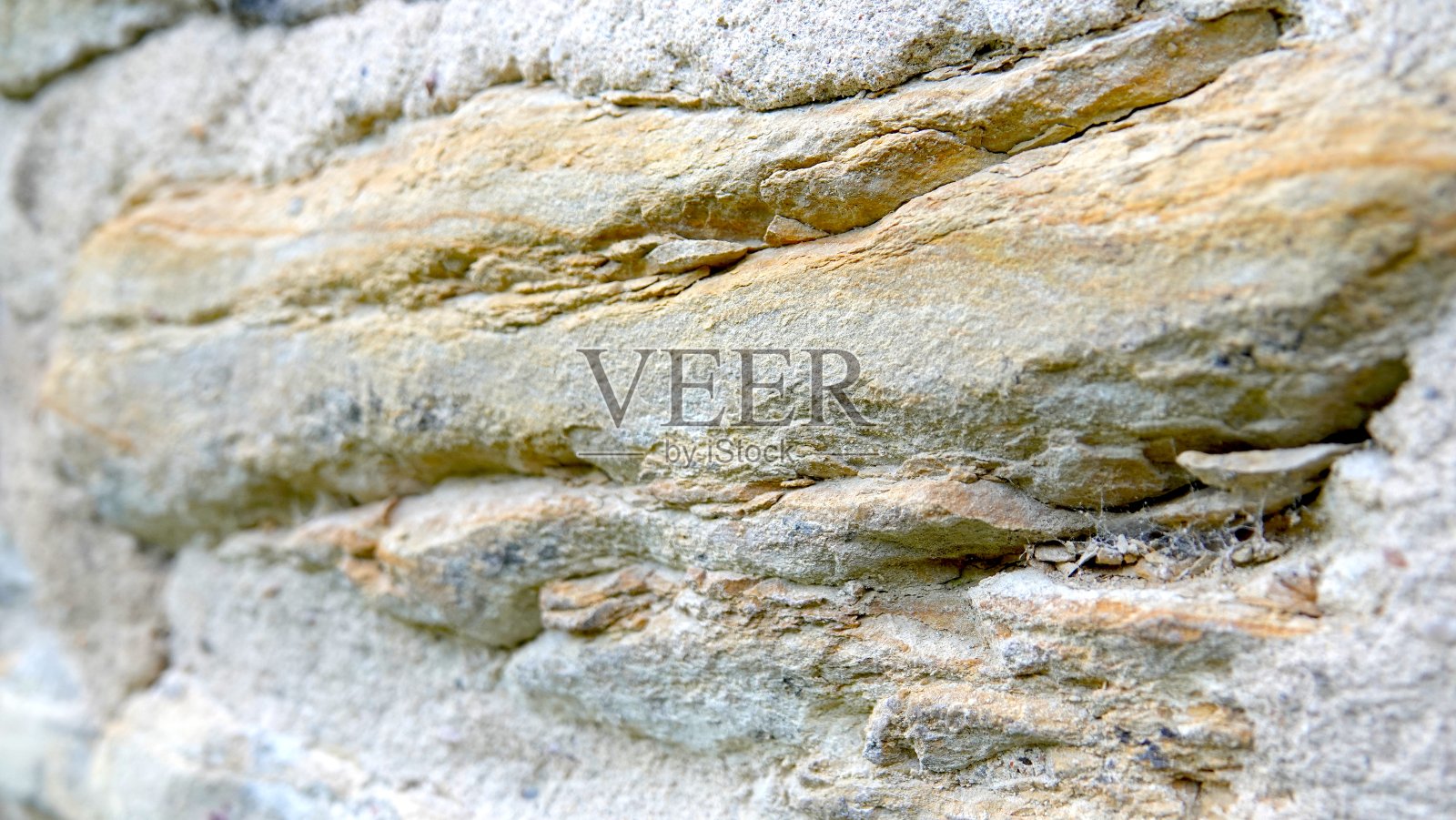 灰黄色,未经处理,自然粗糙的石灰石表面,有几层光影效果(部分模糊)照片摄影图片