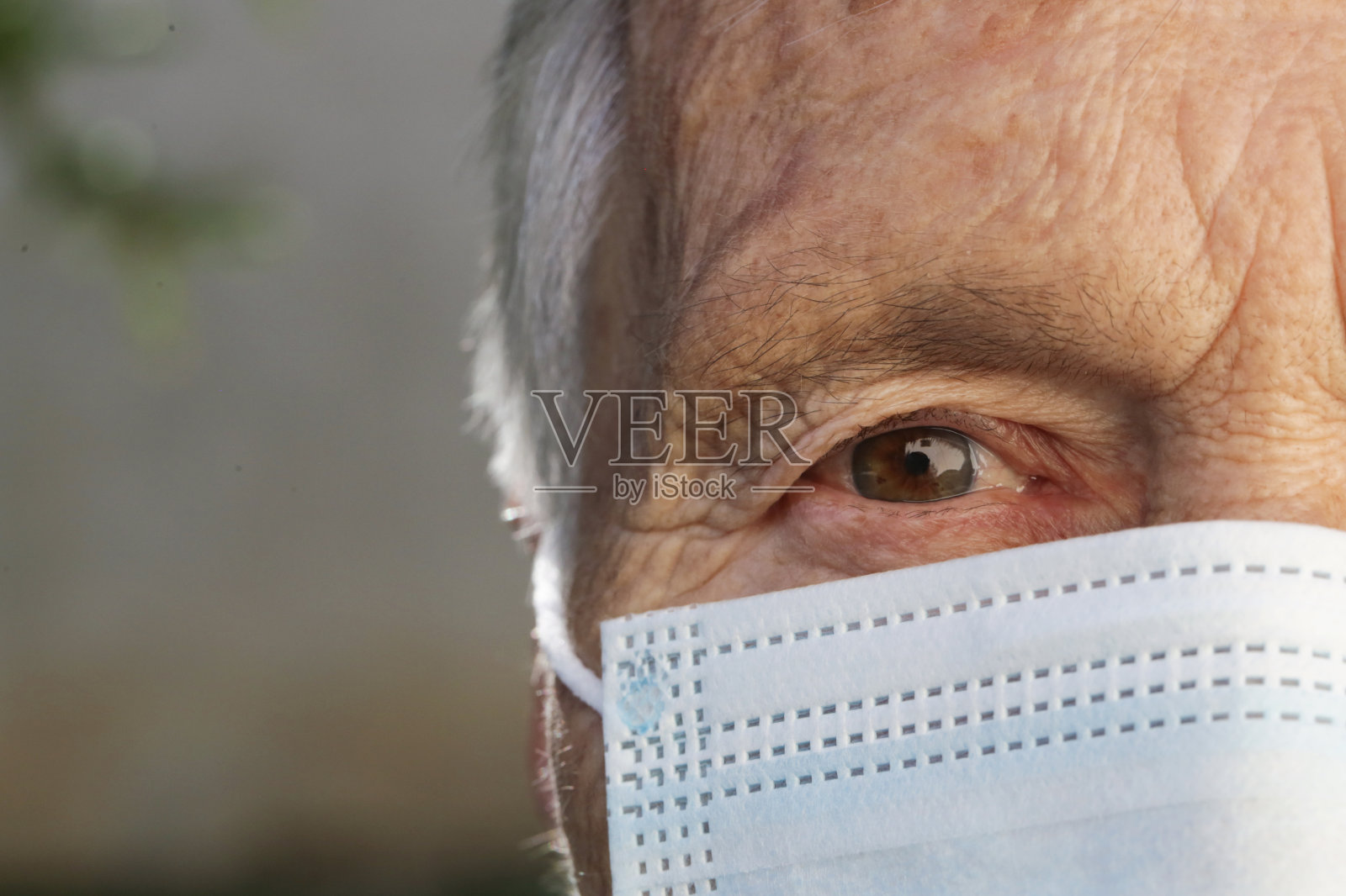 老年白人妇女戴着医用防护口罩的肖像。冠状病毒爆发期间的安全措施。照片摄影图片