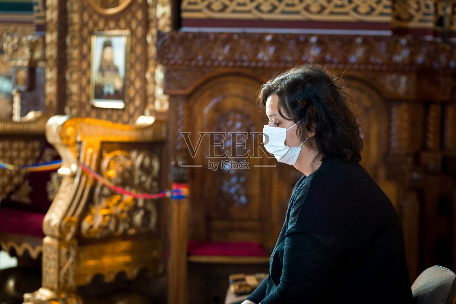 在天主教教堂祈祷的妇女戴着防护面具照片摄影图片