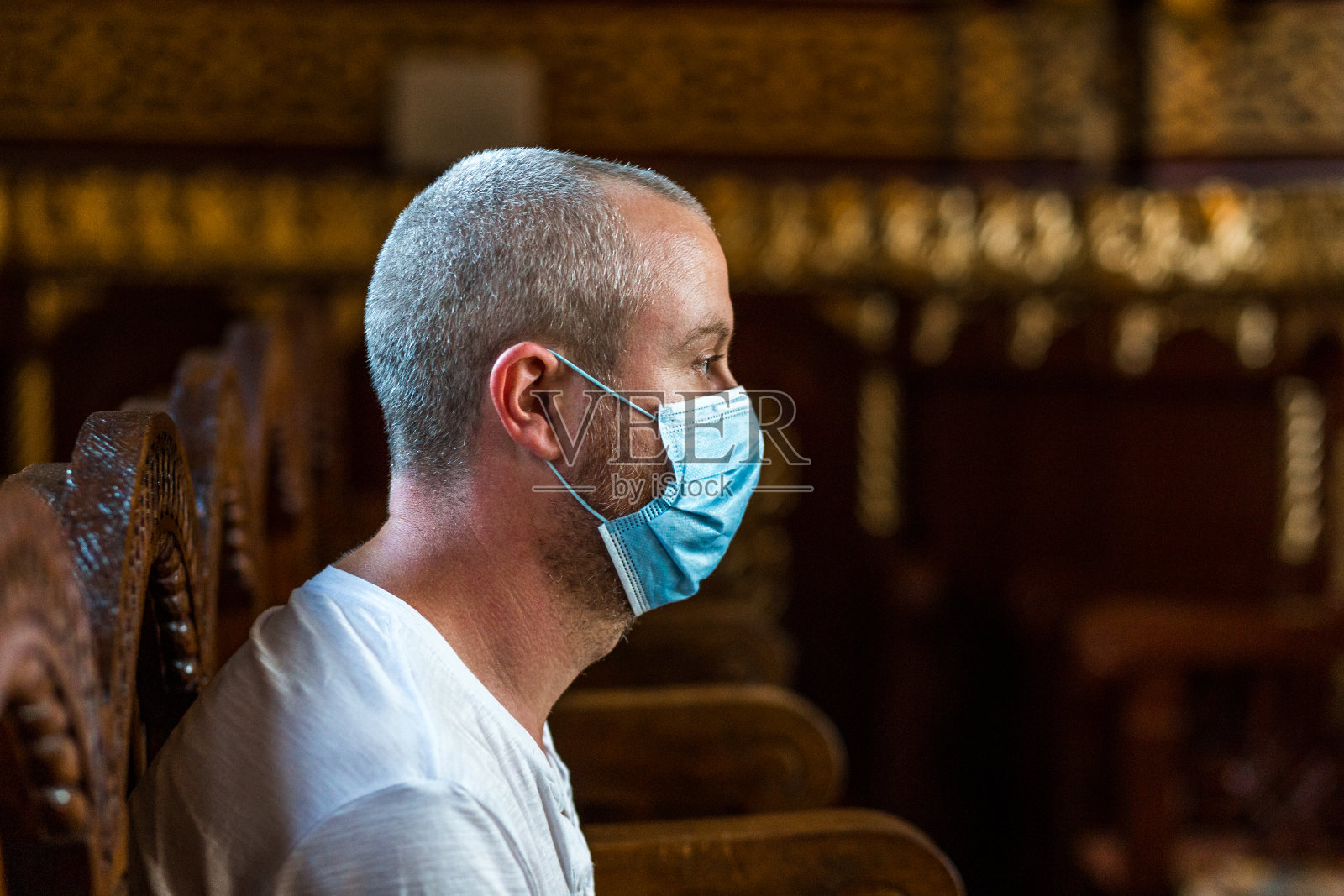 戴着防护面具在教堂祈祷的男子照片摄影图片