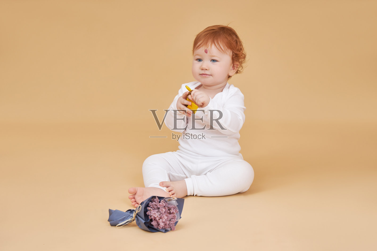 红头发的小女孩在米色的背景上玩耍。额头上有颗大痣,跟别人不一样照片摄影图片