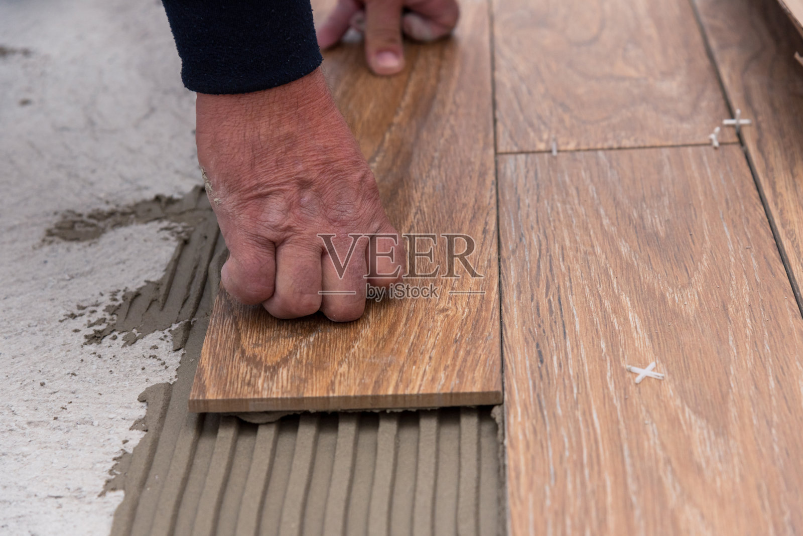 工人在胶粘剂表面铺设瓷砖,找平照片摄影图片