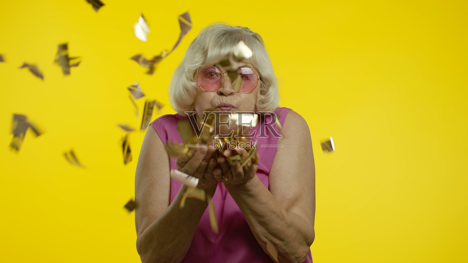 40、快乐的老夫人大笑着,吹着闪闪发光的五彩纸屑,庆祝生日,中彩票照片摄影图片