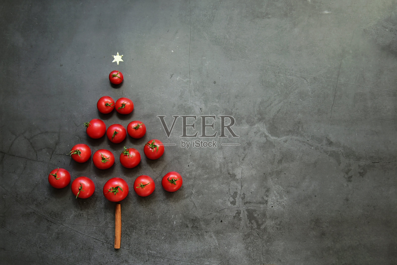 黑色背景的圣诞桌子与红色的樱桃番茄的形式的圣诞树。平面造型风格。新年贺卡。空间的文本。照片摄影图片