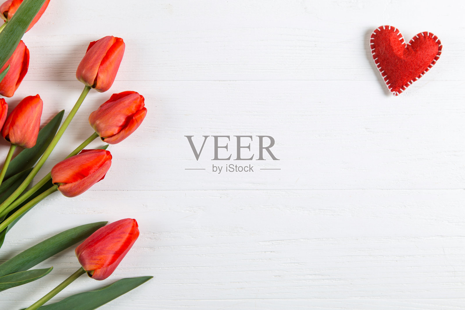 白色的桌子上放着红色的郁金香和心形,背景是空白的明信片。副本的空间。照片摄影图片