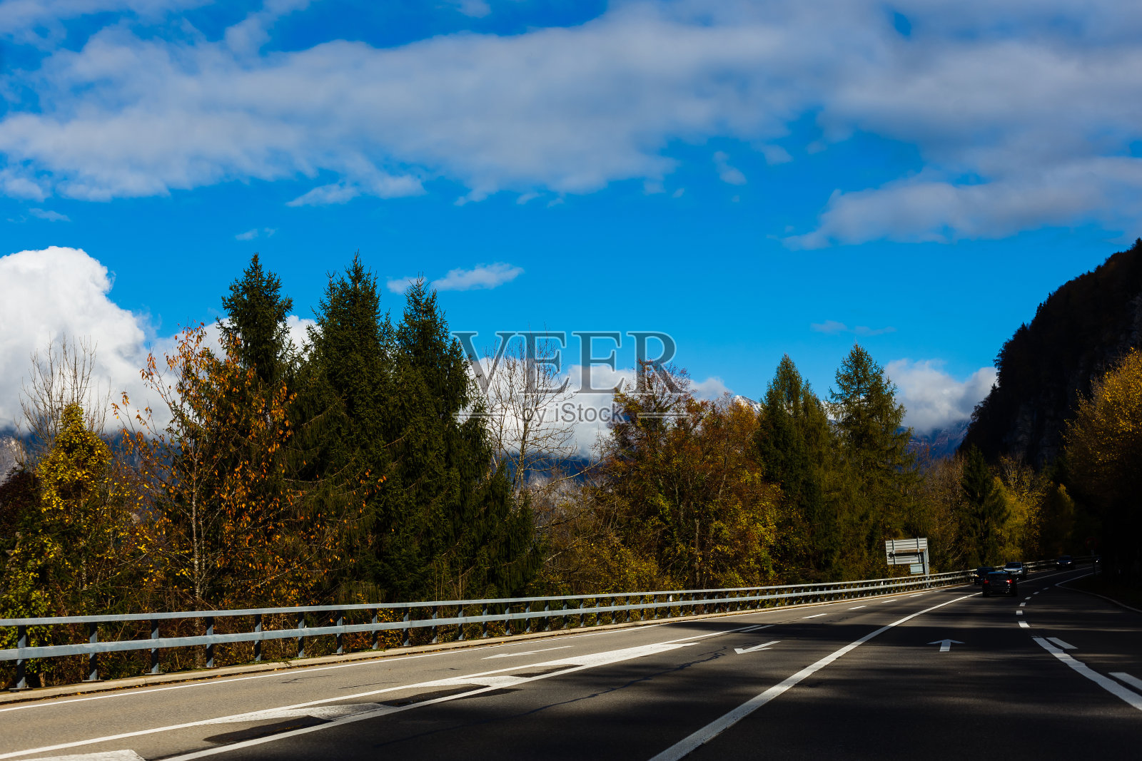 秋天日出时的柏油路。风景优美,空旷的山路上有完美的沥青,高高的岩石,树木和阳光灿烂的天空。古董塑身。旅游的背景。在山区高速公路。速度照片摄影图片