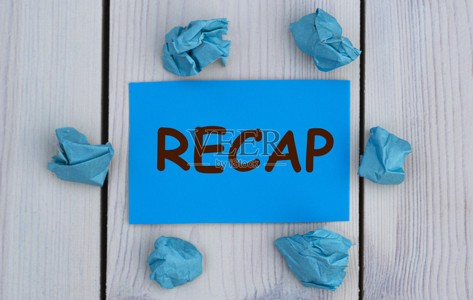 重述-单词在蓝色的纸上,在浅的背景和皱巴巴的纸照片摄影图片