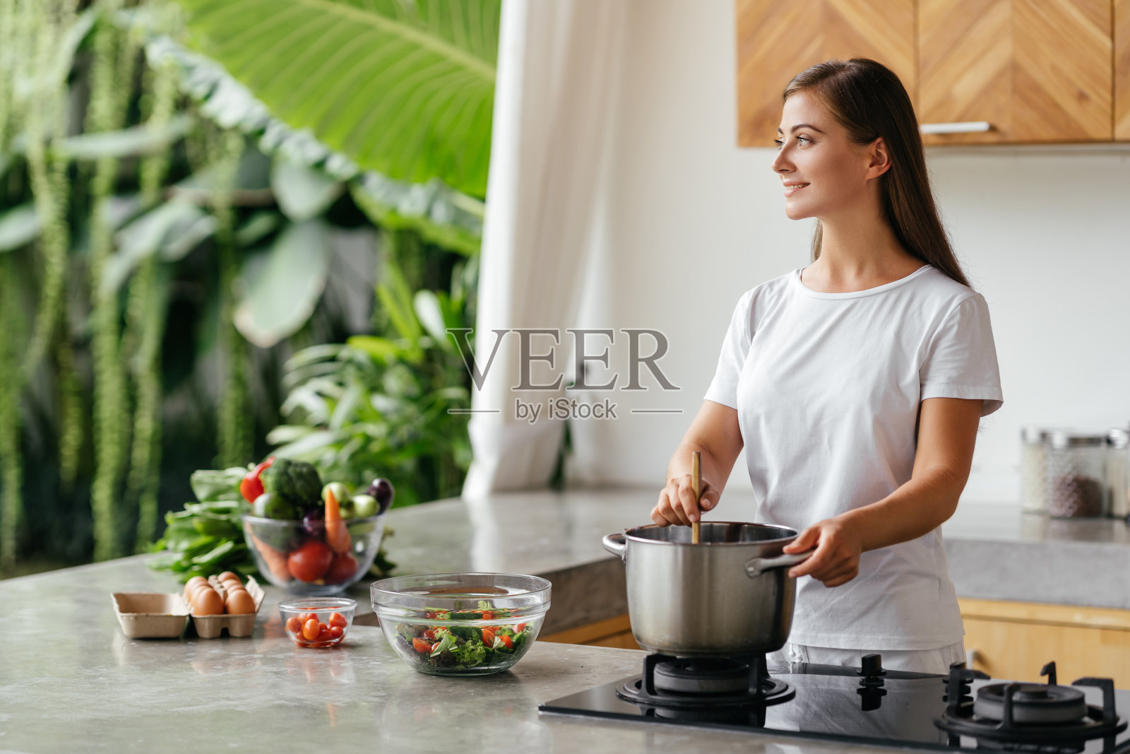 漂亮的白人妇女拿着勺子在煮新鲜蔬菜汤的照片照片摄影图片