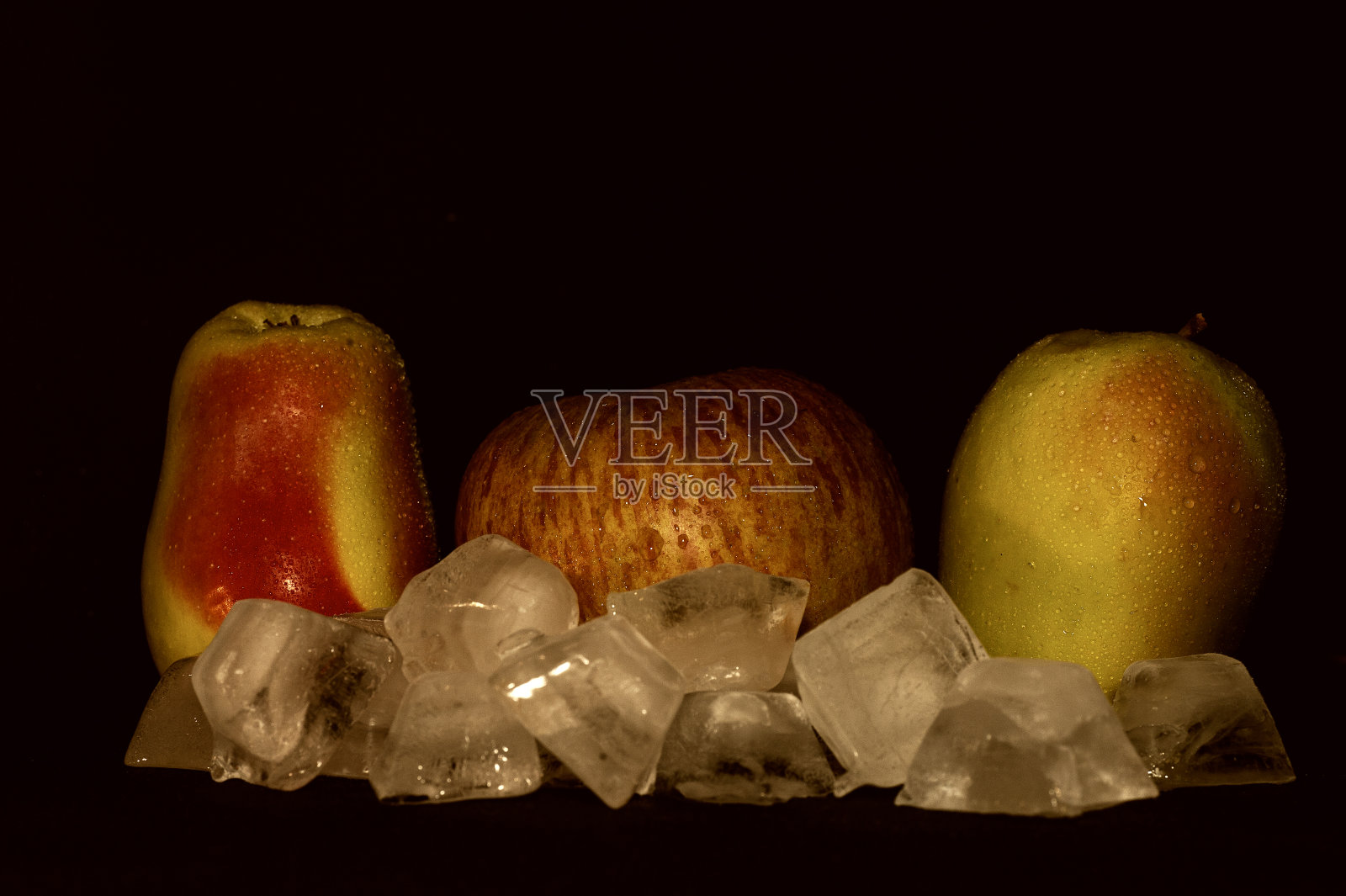 三个红和绿苹果与冰滴在一个黑色的背景特写照片摄影图片