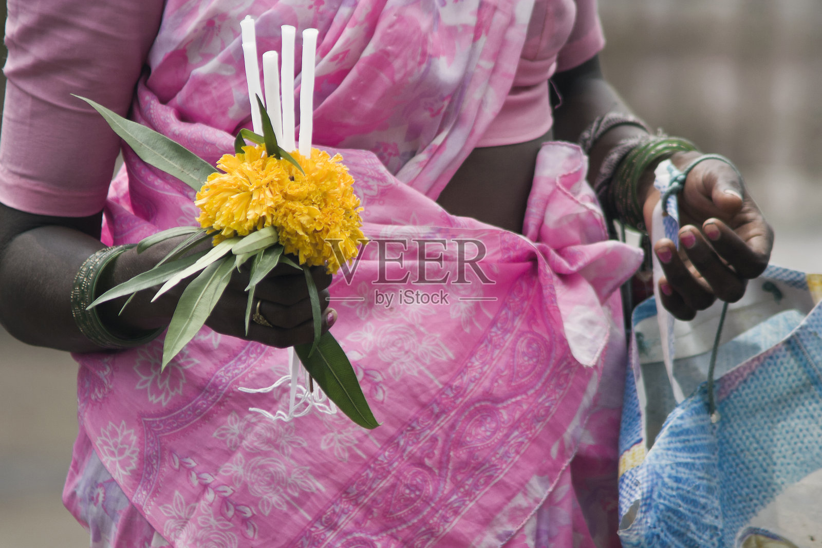 一个女人的手拿着鲜花和蜡烛在街上出售的特写。照片摄影图片