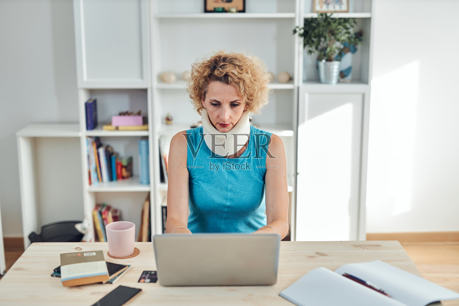 颈部/颈部和颈部/脊椎受伤的女性在家用笔记本电脑工作。照片摄影图片