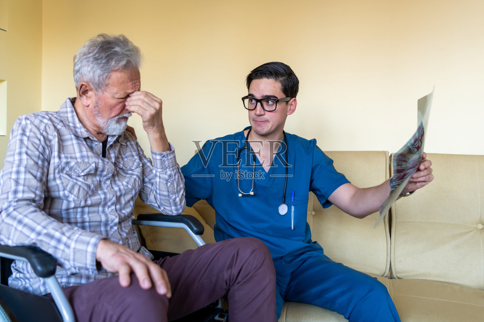 家庭护工正在给一位坐轮椅的老人展示x光图像照片摄影图片