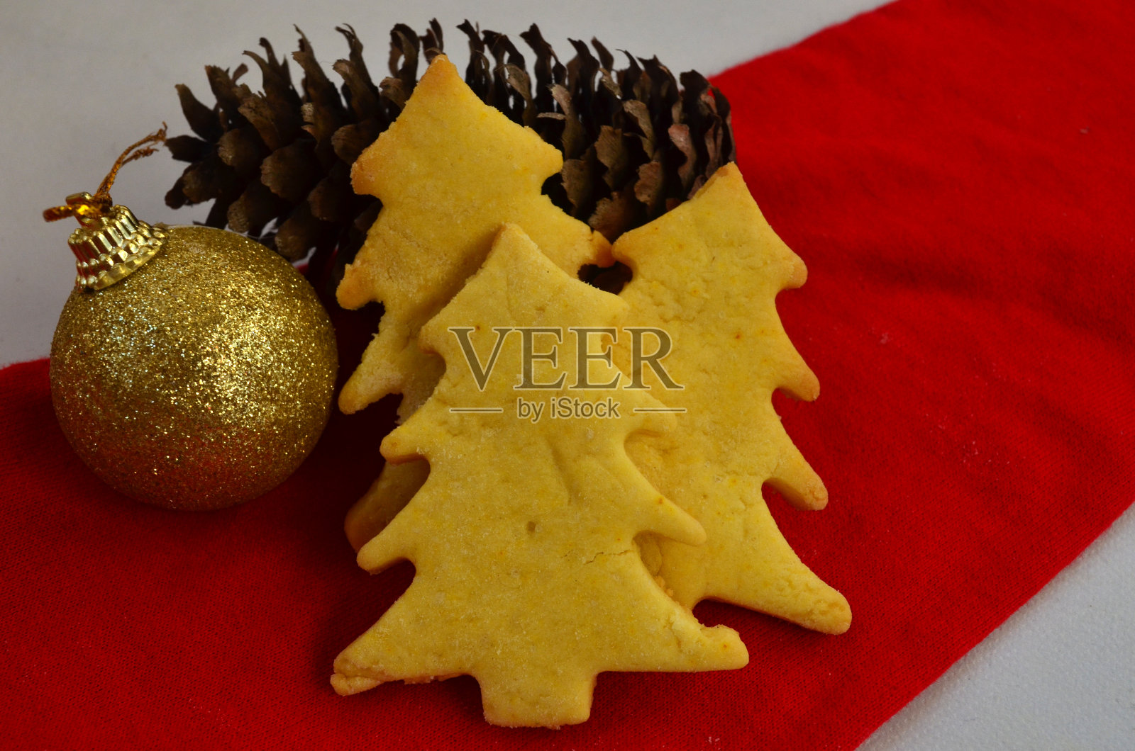 圣诞树形状的酥饼,红色背景上有新年的装饰。圣诞节。照片摄影图片