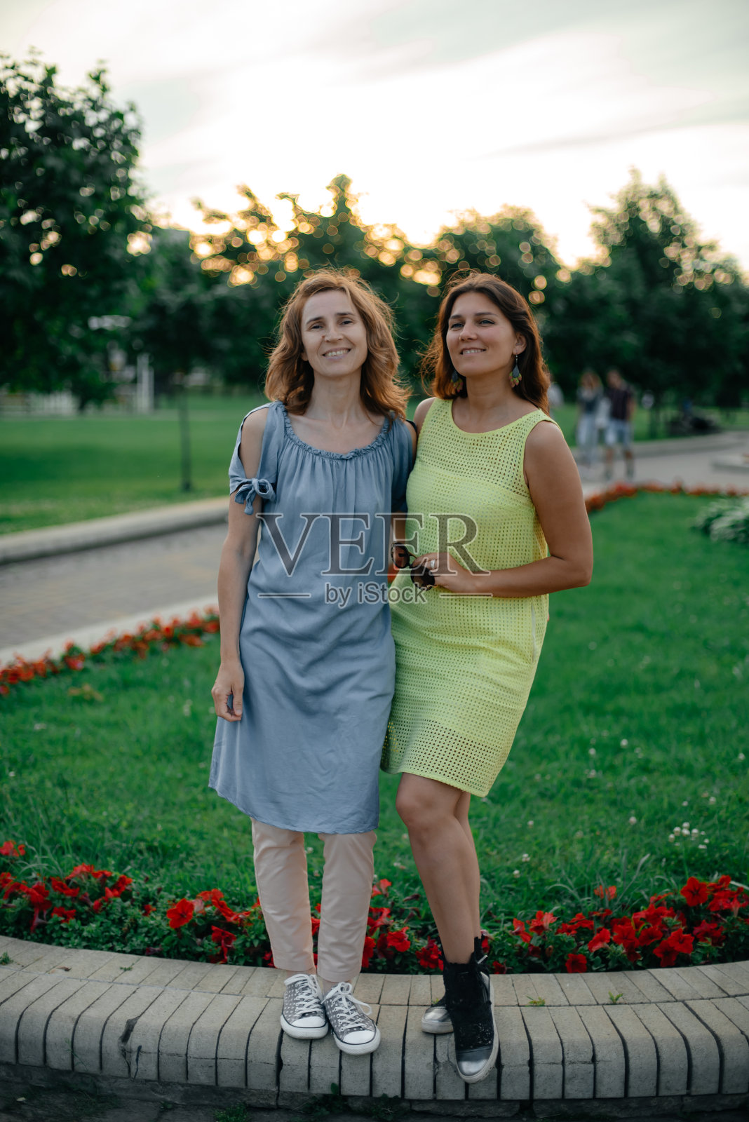 在一个阳光明媚的夏日,妈妈和女儿在公园里休息。照片摄影图片