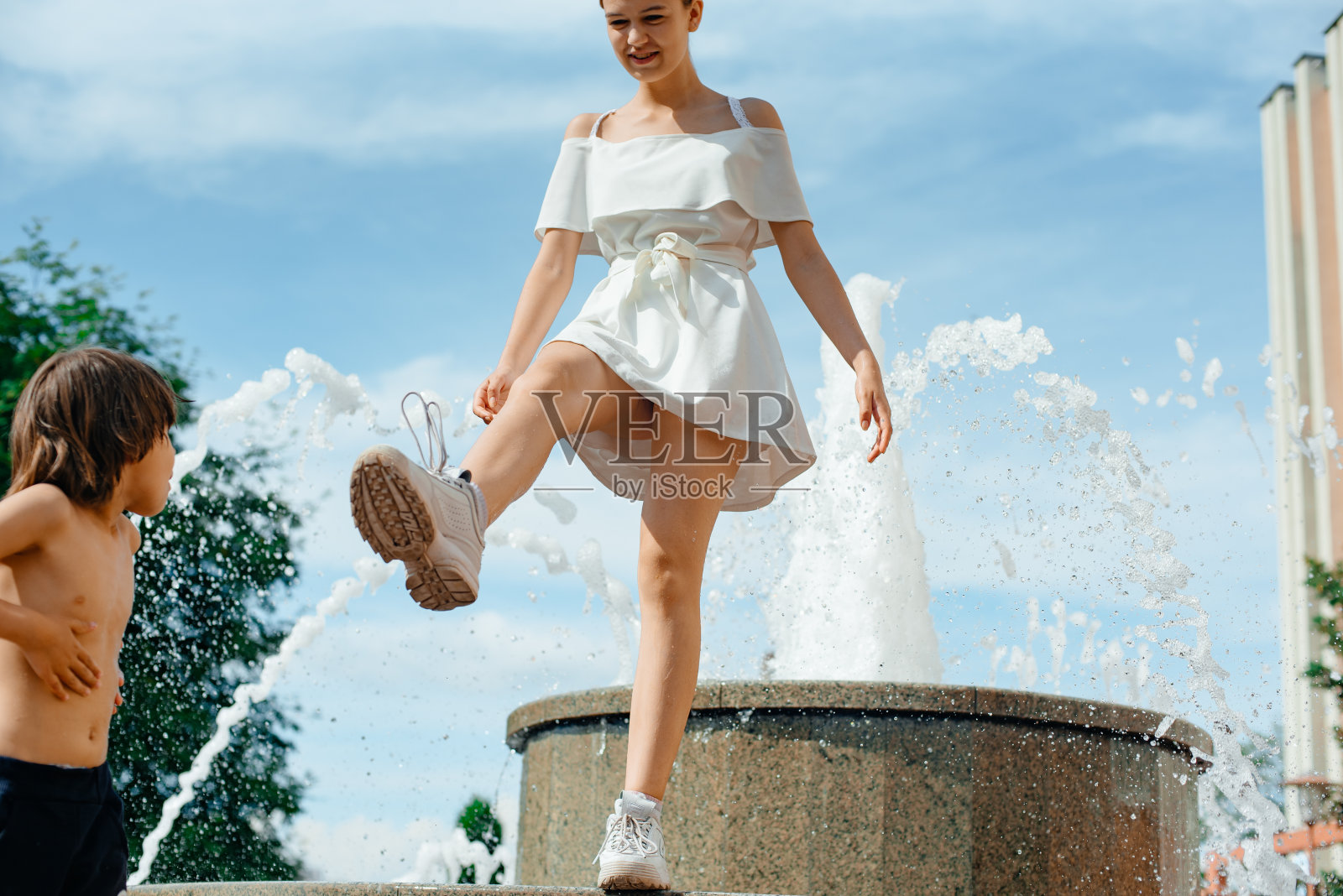 一个小女孩在城市的喷泉附近散步。照片摄影图片