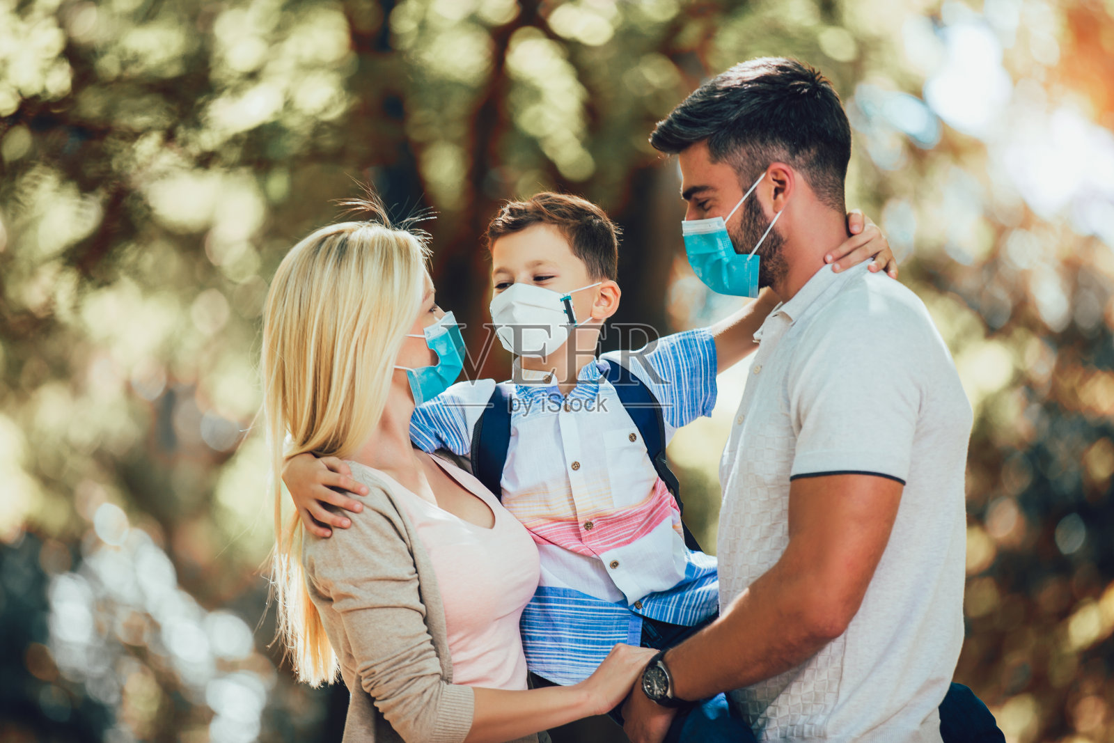 在公园里,家人戴着防护口罩以防止病毒感染。照片摄影图片