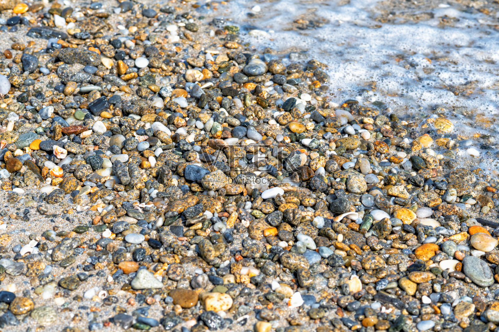 卵石海滩和水为背景。不同形态的矿物作为自然抽象纹理的多色背景照片摄影图片
