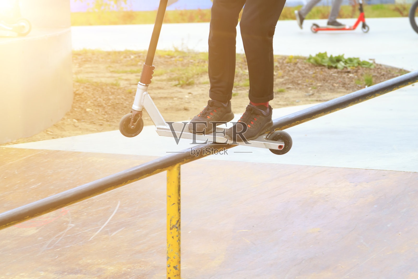 骑车人在滑板车上沿着滑板公园的金属坡道边缘滑行照片摄影图片