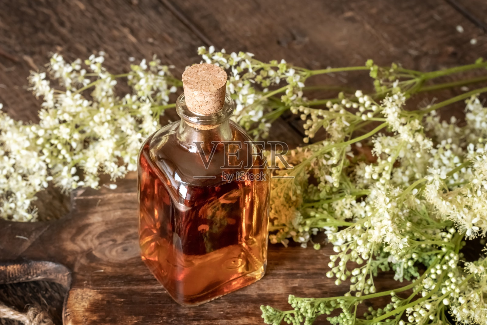 一瓶自制绣线菊酊,里面有新鲜盛开的绣线菊照片摄影图片