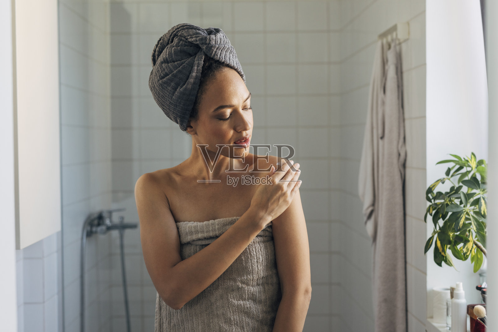 女人用身体乳液她的皮肤,自我护理概念照片摄影图片