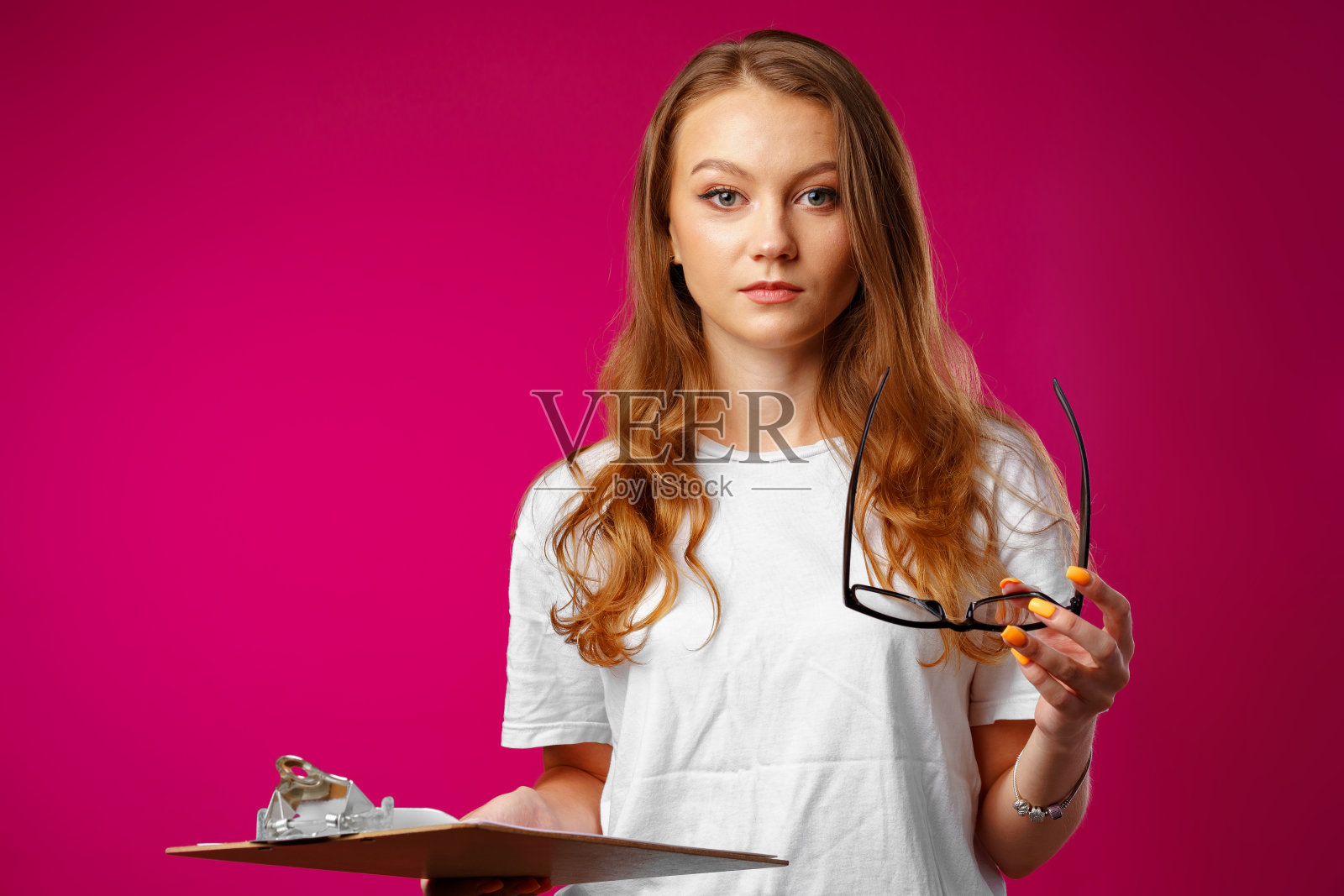 年轻美丽的微笑女人站着拿着写字板照片摄影图片