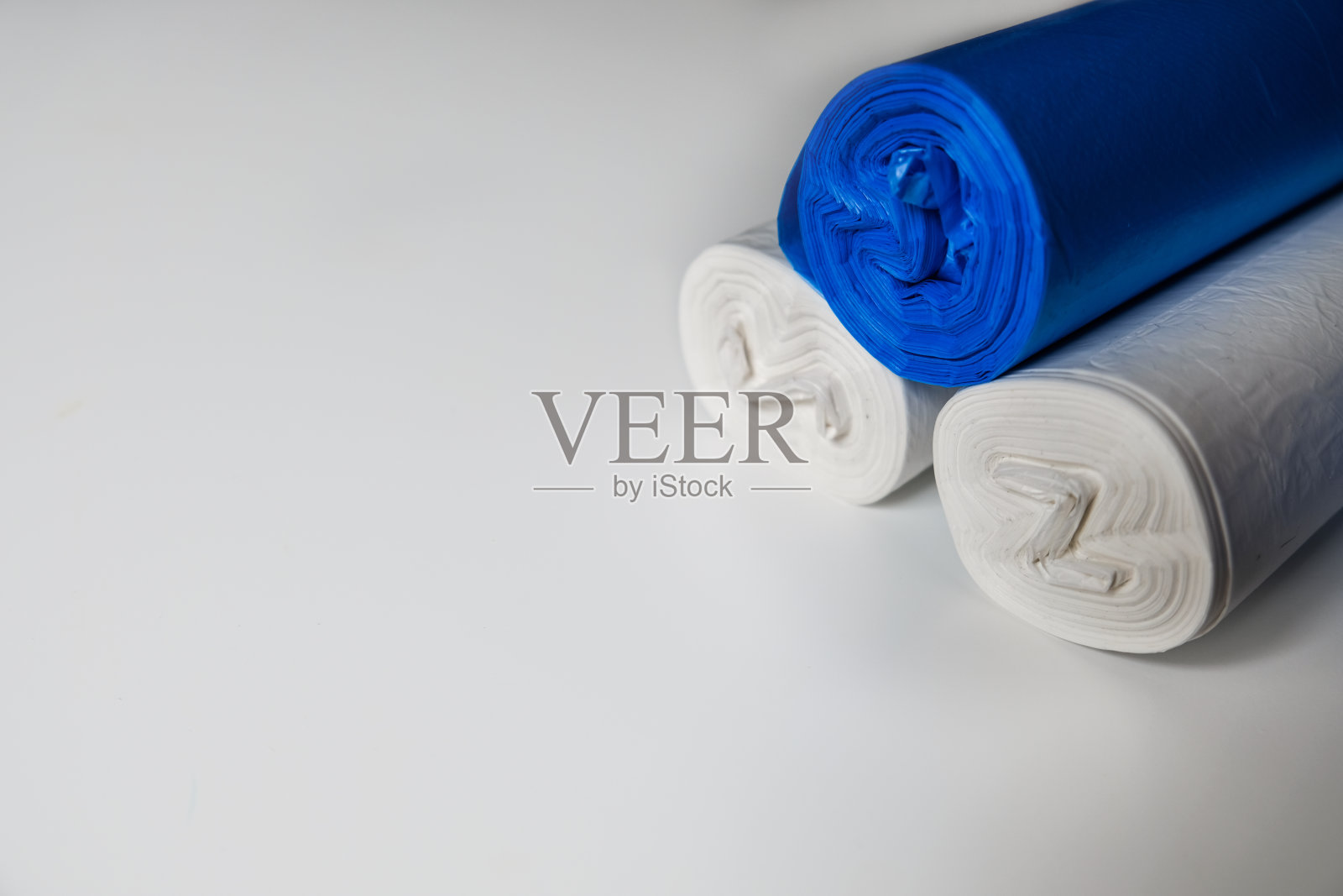 白色表面上的蓝色和白色塑料垃圾袋。照片摄影图片