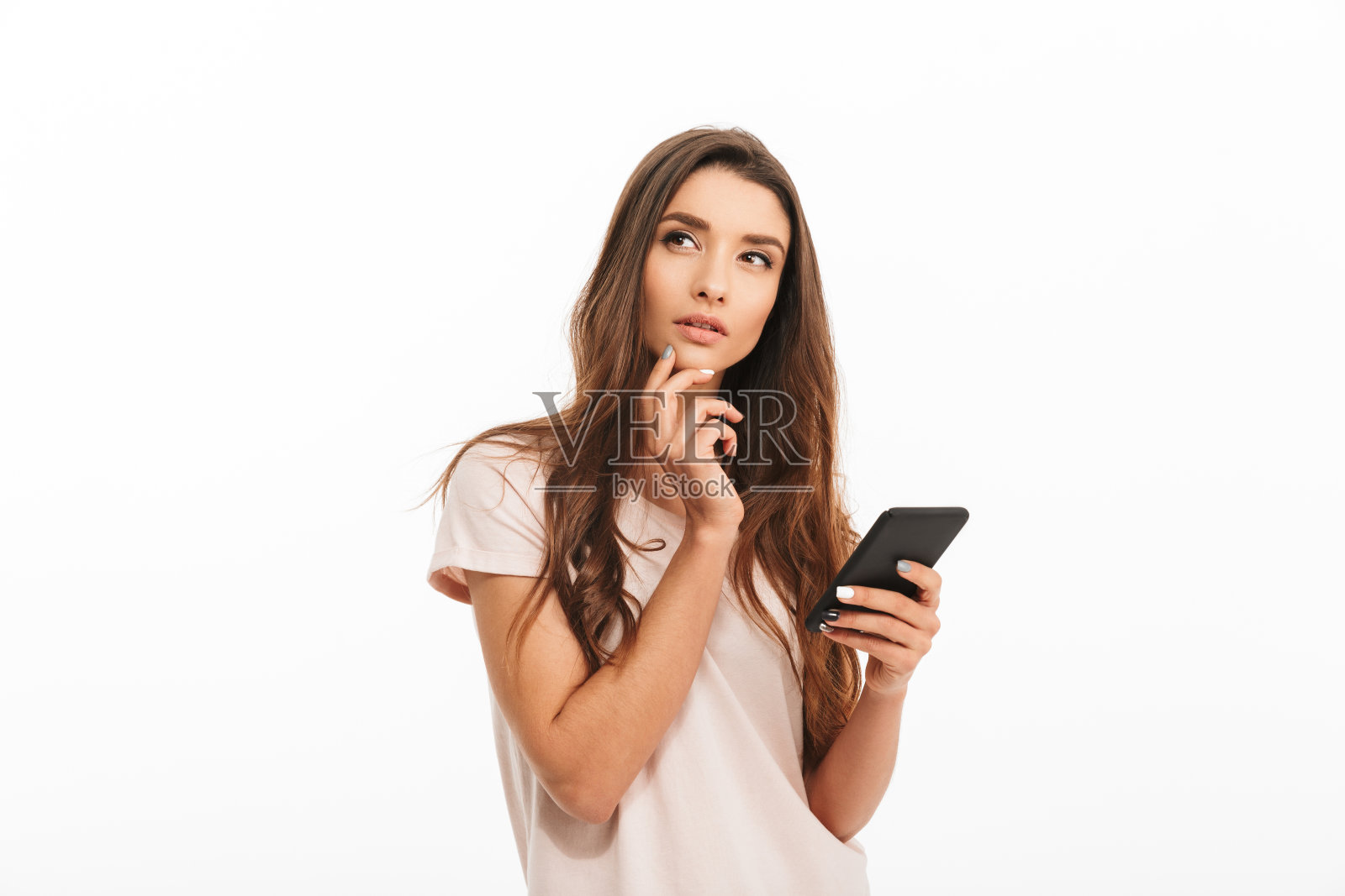 沉思的黑发女人,穿着t恤,拿着智能手机,看向别处照片摄影图片