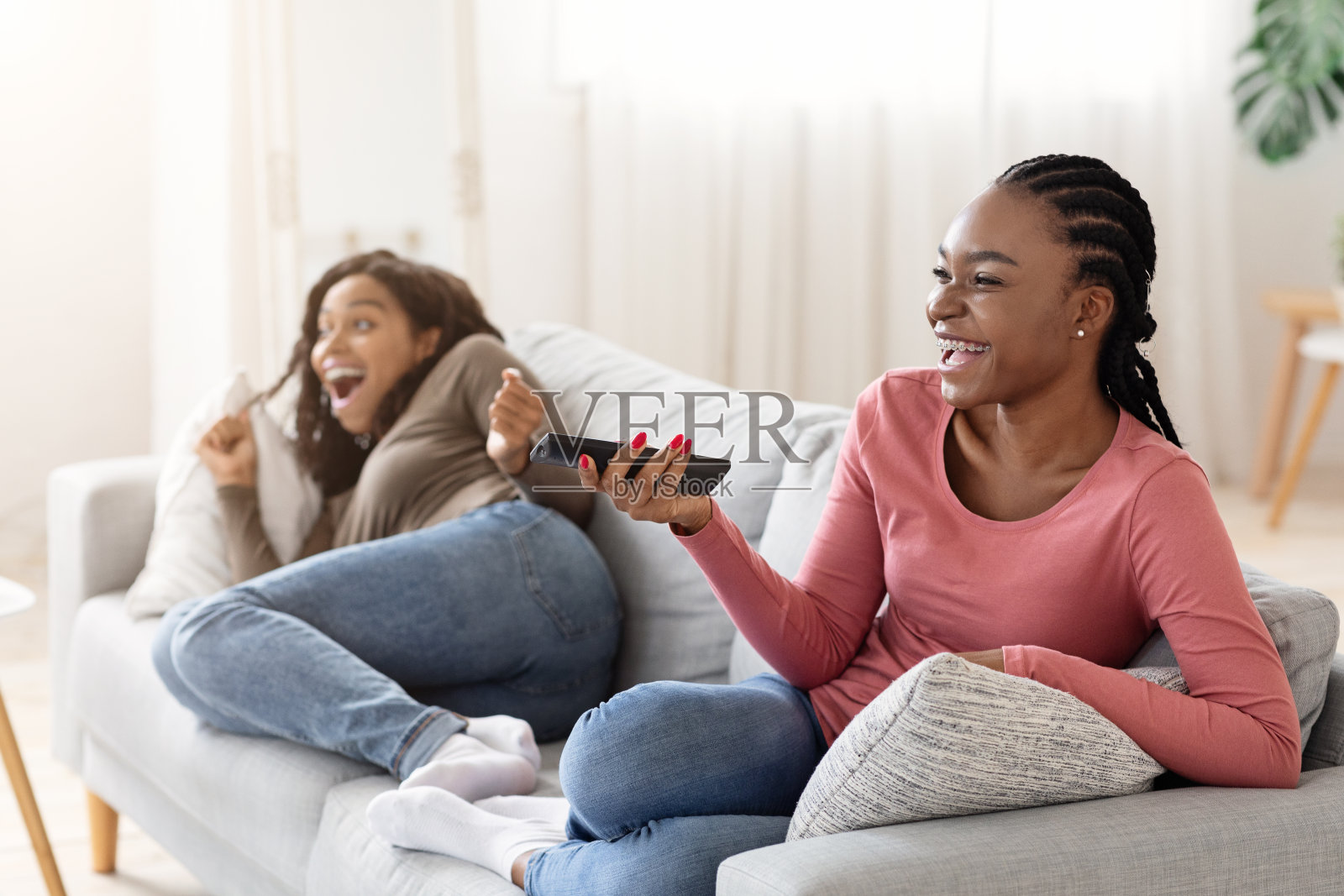 快乐的非洲女孩在家里看电视照片摄影图片