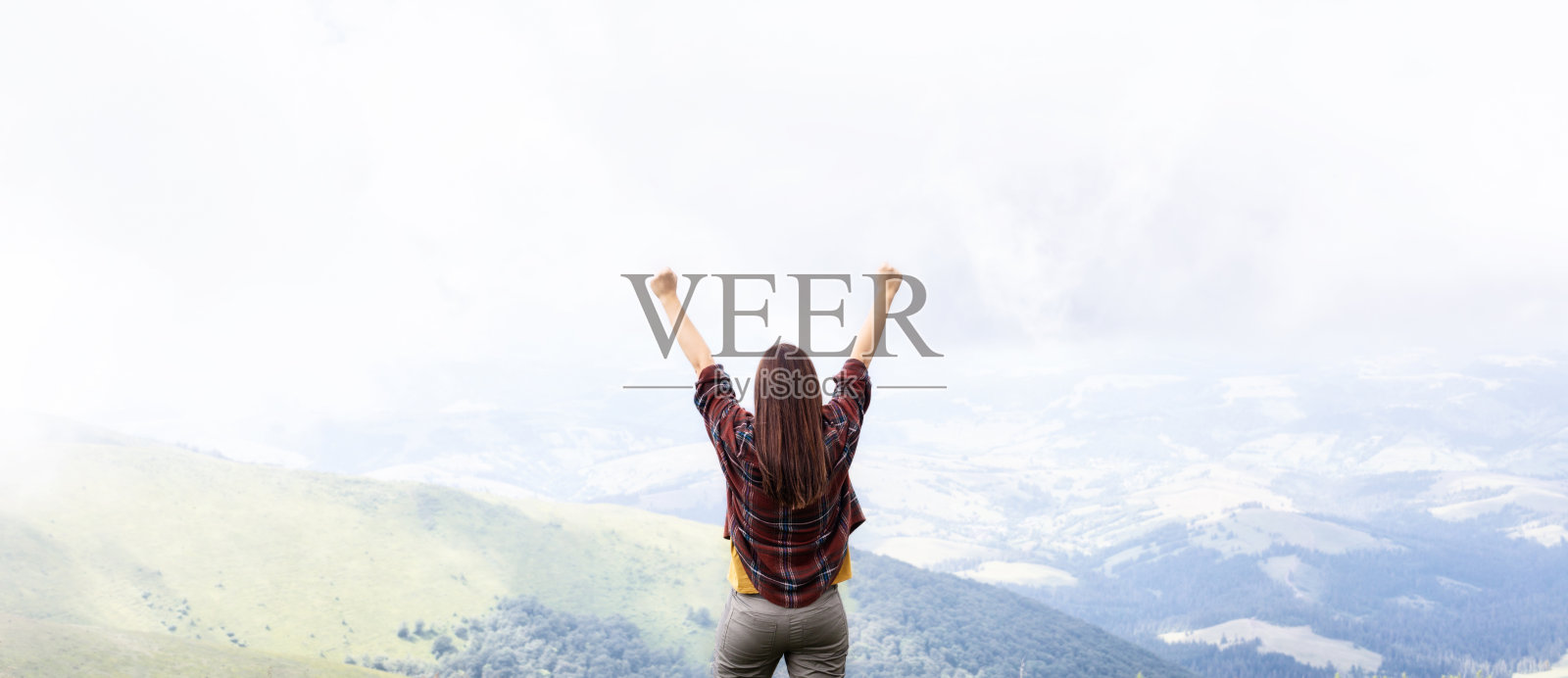 女人举起双手站在山顶上欣赏风景照片摄影图片