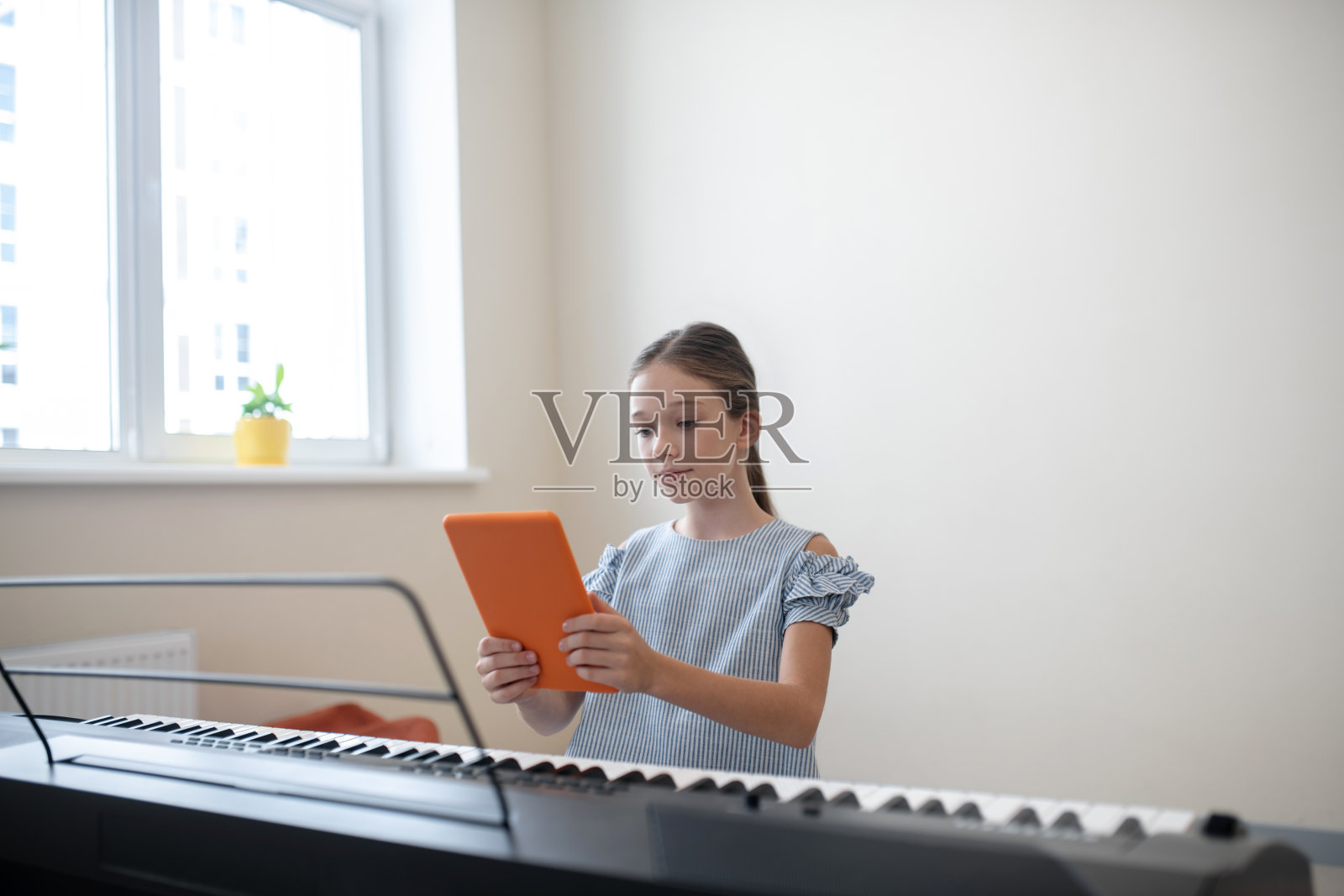 蓝色裙子的长发女孩坐在合成器前,手里拿着一个平板电脑照片摄影图片